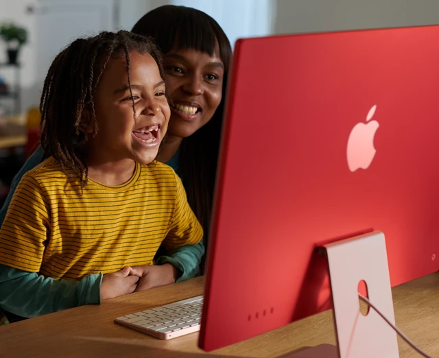 فردان من العائلة يضحكان سوياً أثناء مشاهدة برنامج على iMac‏