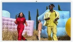 Three people in bright outfits, surrounded by colorful inflatable shapes