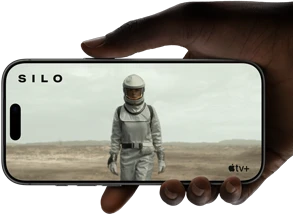 A hand holds an iPhone 17 Pro, Silver, horizontal, video playback on all-screen display demonstrating battery life