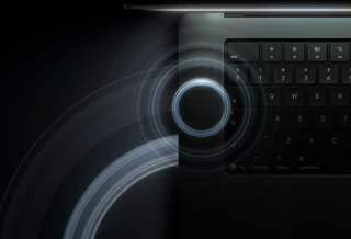 MacBook Pro with PROLED XDR Display, open lid, space black color, keyboard lit by glow from display, circles depicting sonic waves emanate from top and left side of laptop body